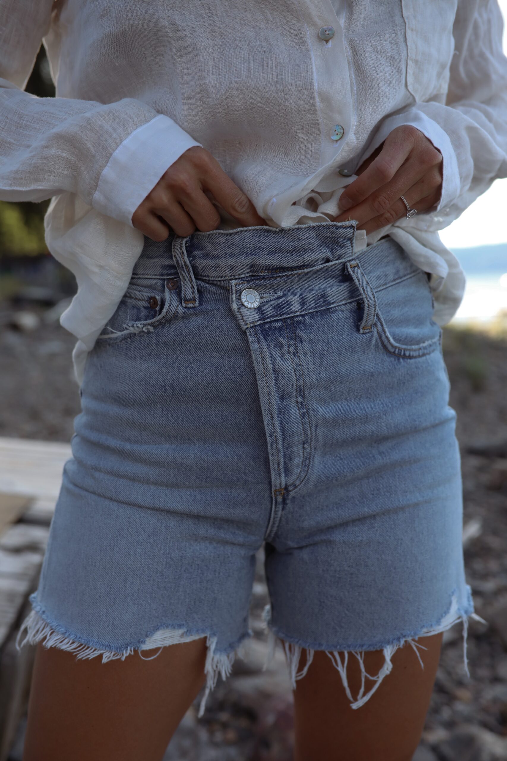 Photo of girl wearing cut off light blue shorts with a linen white t shirt tucked in.