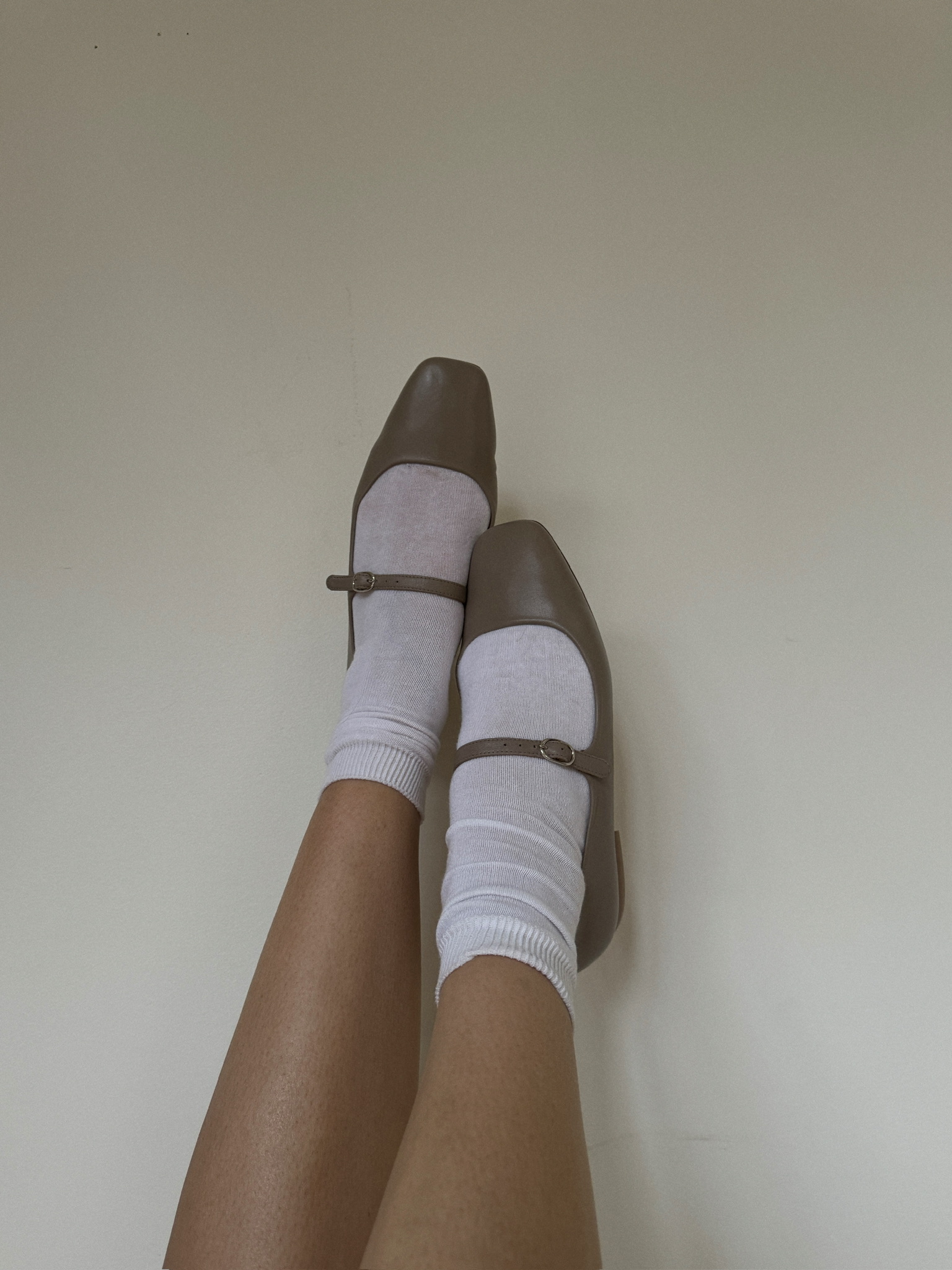 Image of feet on walls wearing mary janes with white socks underneath.